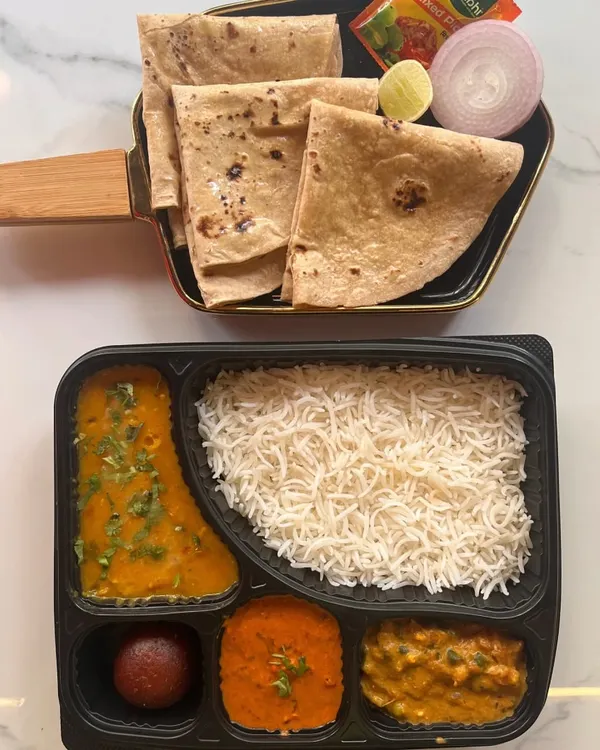 A classic North Indian vegetarian thali, neatly packed and ready to serve. This meal box includes two vegetable curries, dal, steamed rice, rotis, and a gulab jamun, offering a complete and traditional dining experience for your event.