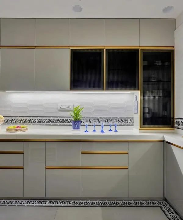 This kitchen is a masterclass in modern elegance. Sleek grey cabinets with gold handles, a patterned tile border, and under-cabinet lighting create a look that is both sophisticated and highly functional.
