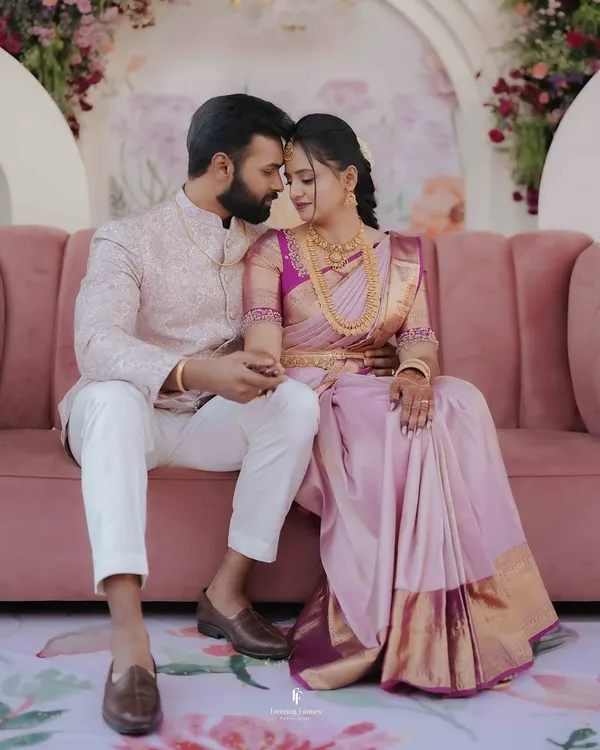 A tender moment between the newly engaged couple, seated on a pink sofa surrounded by beautiful floral decor. This is the kind of serene portrait I love to create.