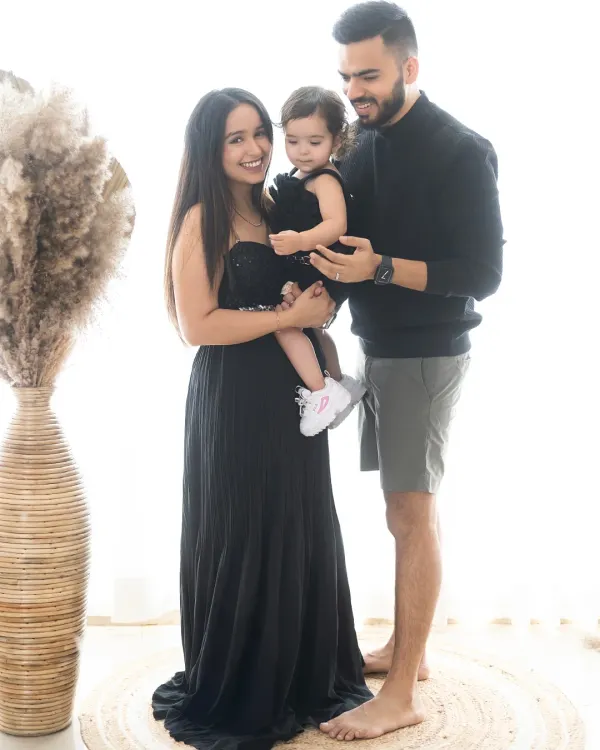 A lovely candid family portrait. The parents are sharing a smile while holding their little girl, a simple, happy moment captured forever.