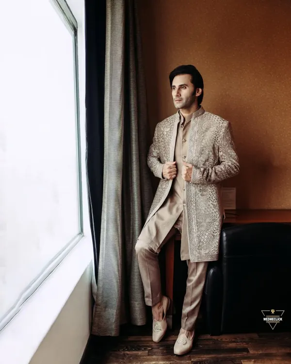 A classic portrait of the groom looking out the window, lost in thought before the ceremony. This shot captures a moment of quiet anticipation and his sharp style.