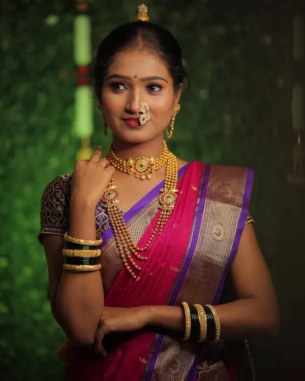 The grace of a Nauvari saree is unmatched. Here, my client is styled in a traditional pink and purple nine-yard saree with layered gold jewelry and a classic Maharashtrian nath.