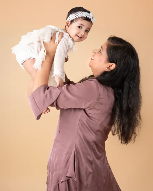 A mother's joy as she lifts her baby girl high. These are the playful, candid moments that make the best memories.