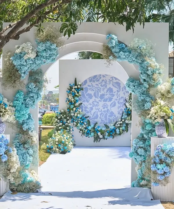 The entrance to this French-inspired carnival featured a grand floral arch in shades of blue and white. The design, with its clean lines and abundant hydrangeas, set a fresh and welcoming tone for the daytime celebration.
