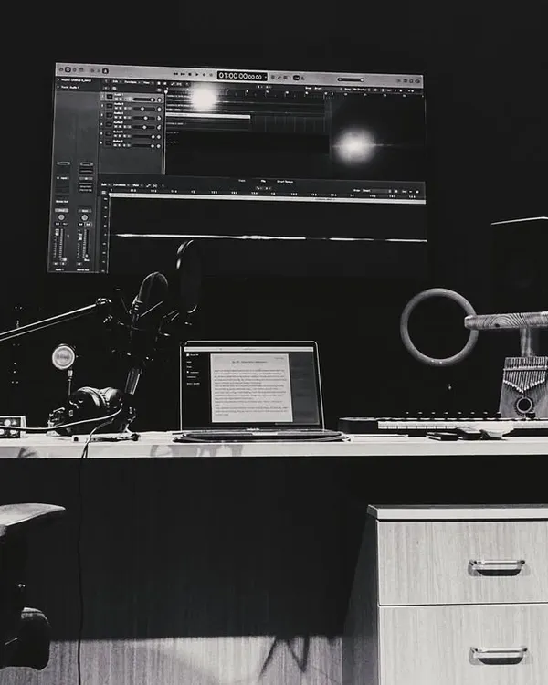 A black and white photo of my home studio setup. This is where the magic happens, from doodling lyrics on my laptop to recording the final vocals.