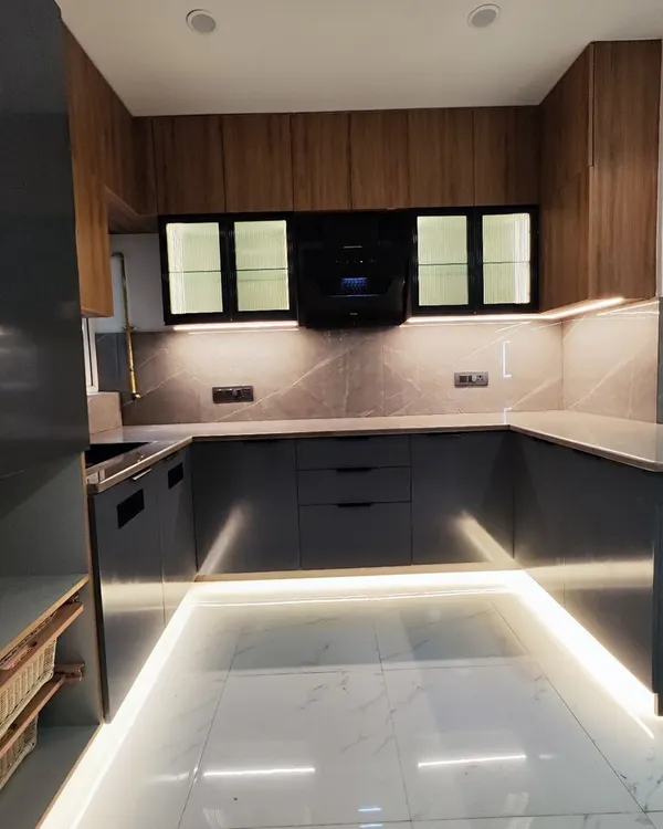 This is a full view of a U-shaped modular kitchen I completed. The design uses a combination of wood-laminate overhead cabinets and matte grey base cabinets, with profile lighting along the floor to add a modern touch.