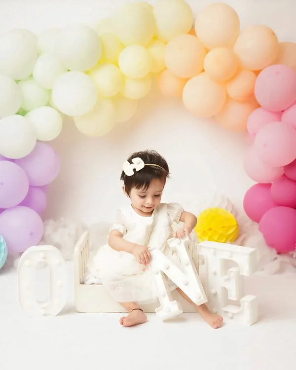 A candid moment from a first birthday shoot, as the little girl plays with the 'ONE' letters. I love capturing these moments of discovery and play.