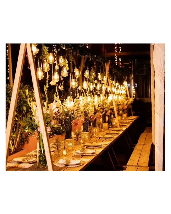 We specialize in creating immersive dining experiences. This rustic-chic anniversary dinner features a long table setup under a canopy of warm Edison bulbs and lush greenery, setting the perfect mood for an intimate and elegant celebration.