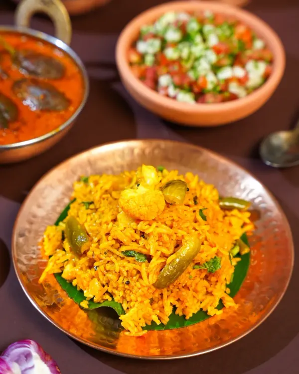 A close-up of Tondli Bhaat, a classic Maharashtrian rice dish, served on a banana leaf atop a copper plate. The styling highlights the simple, wholesome ingredients that define home-style Marathi cooking.