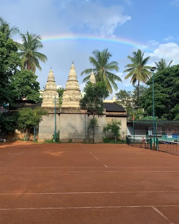 A stunning view of our court with a rainbow overhead, right next to the serene temple. This truly captures the "divine tennis experience" we aim to provide.