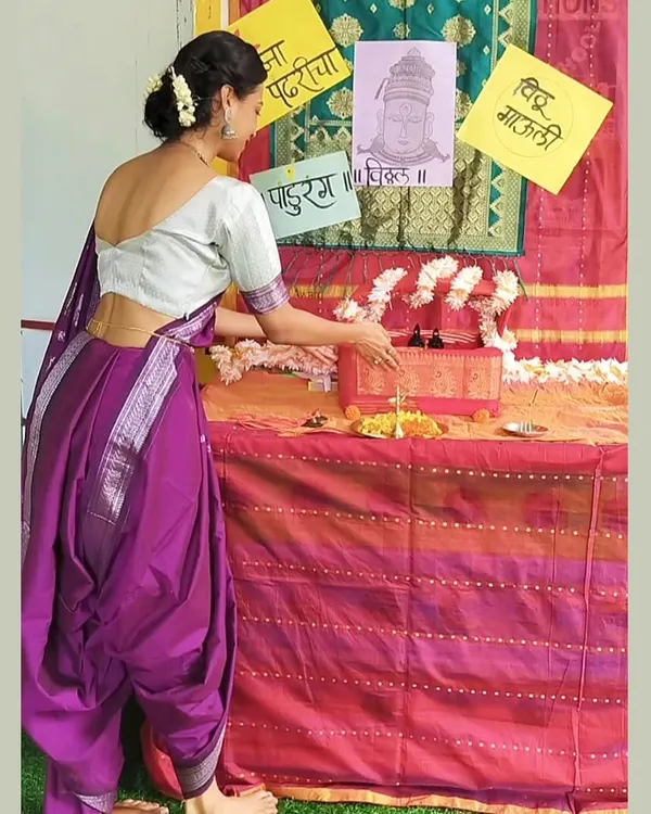 Dressed in a traditional Nauvari saree, I am preparing the puja setup for our Ashadhi Ekadashi celebration. It is important for me to share these beautiful cultural practices with the children.