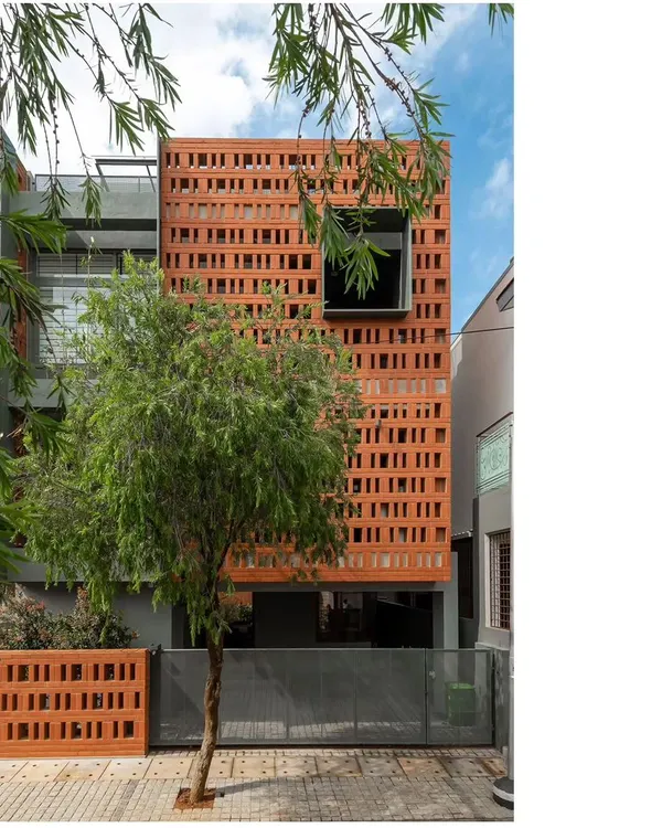 The defining feature of the 'Big-Little House' is its perforated brick facade. This screen provides privacy for the service areas located at the front while allowing for natural ventilation and creating a unique, textured architectural identity.
