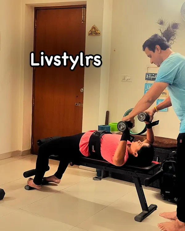I am spotting a client during a dumbbell chest press. This ensures she can push her limits safely while maintaining correct form for chest and shoulder strength.
