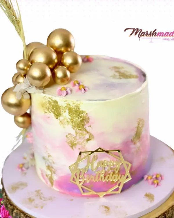 Tall cakes are so chic, and I love creating them. For this birthday cake, I used a watercolour buttercream technique with delicate gold foiling and a cascade of golden spheres for a modern, celebratory look.