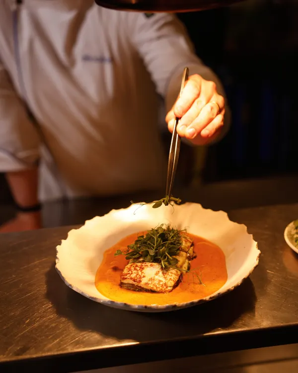 Our chef meticulously adds the final garnish to a dish. This attention to detail is at the heart of our culinary philosophy.