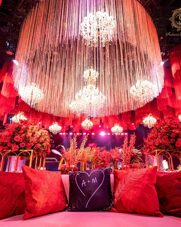 A glimpse into a Sangeet where passion took center stage. This custom monogrammed velvet cushion sits before a cascade of crystal and fabric, under the warm glow of grand chandeliers, setting a tone of unapologetic luxury and personal storytelling.