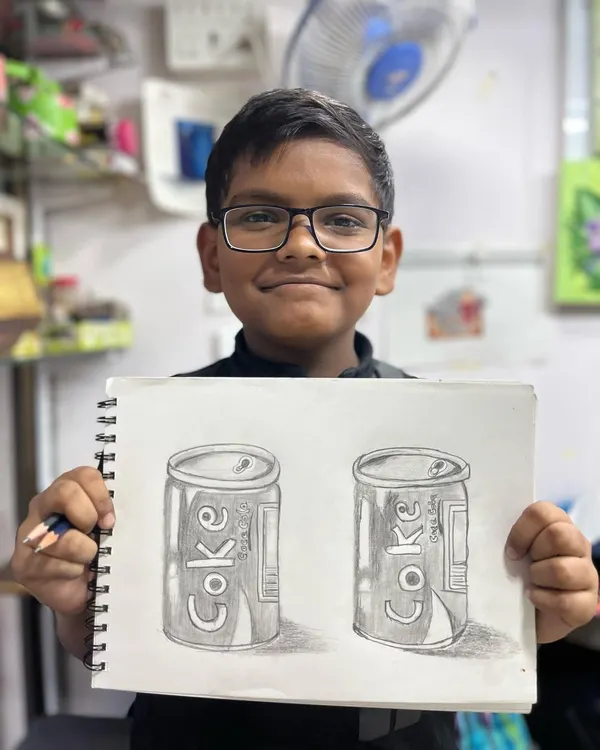 We are incredibly proud of this 9-year-old student's progress after just six sessions of pencil shading. He is proudly displaying his detailed sketch of a Coke can, showing great control of light and shadow.