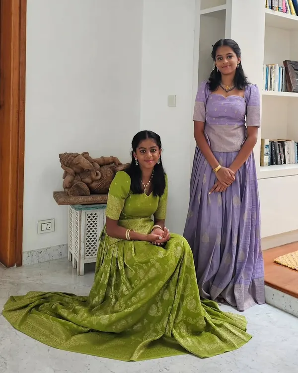 Custom-designed traditional lehengas for two sisters. The lime green and soft lavender brocade outfits feature intricate patterns and are tailored for a perfect fit, allowing each sister to have her own distinct yet coordinated style for the special event.