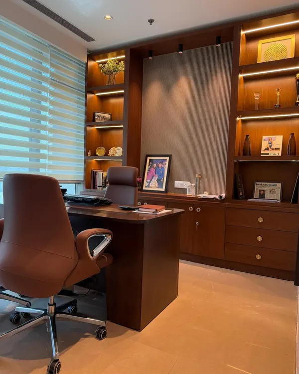 We designed this executive office to be both productive and aesthetically pleasing. The custom-built wooden shelving unit features integrated backlighting to highlight awards and decor, while the ergonomic leather chair and spacious desk provide ultimate comfort. The combination of rich wood tones and soft, layered lighting creates a powerful yet sophisticated workspace.