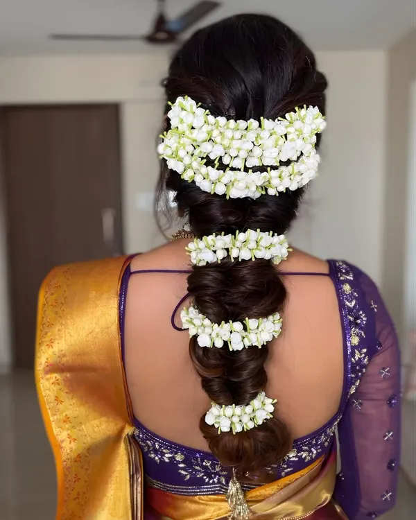 A detailed shot of a traditional South Indian bridal braid, beautifully adorned with fragrant jasmine flowers (gajra). This classic hairstyle is the perfect finishing touch for a traditional look.
