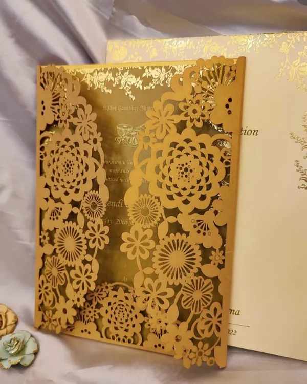 This intricate laser-cut wedding invitation features a floral gatefold design in gold, opening up to reveal the details on a shimmering metallic paper. It's a perfect example of how I combine delicate craftsmanship with a luxurious feel for a truly premium wedding card.