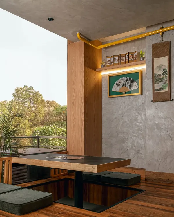 This corner in our Seoul Restaurant project captures the essence of our design approach. We created a sunken seating area with low tables to foster a sense of togetherness, reflecting traditional Korean dining culture. The large window connects the intimate interior with the lush greenery outside, grounding the experience in nature and calm.