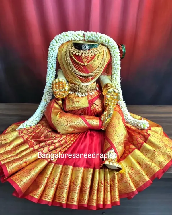 This is the final, majestic look I aim for when draping a saree for Ammavaru. Notice the perfectly fanned-out pleats in this rich red and gold silk saree, creating a full, round base that is ideal for Varamahalakshmi pooja decoration.