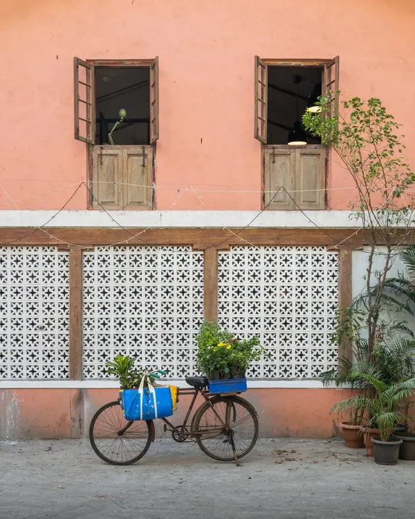 This is the exterior of my studio, an 80-year-old building we rescued. The peach-colored facade, traditional wooden windows, and patterned 'jaali' screen were all lovingly restored. The bicycle with flowers is a nod to the simple, timeless beauty we wanted to cultivate here.