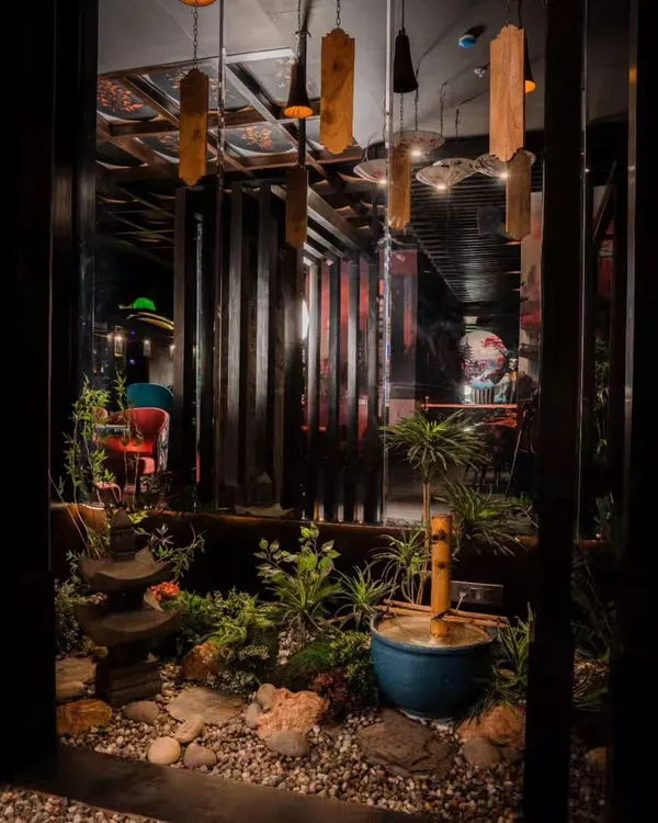 This indoor Zen garden, created for Arigato restaurant, serves as a tranquil centerpiece. The composition of rocks, a bamboo water feature, and subtle greenery provides a peaceful view that enhances the Japanese dining experience.