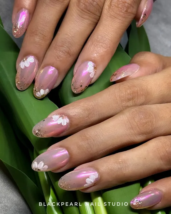 A perfect bridal design featuring a soft pink "glazed donut" chrome base. I added delicate hand-painted white flowers and a chunky gold glitter fade at the tips for a look that is romantic, modern, and incredibly dreamy.