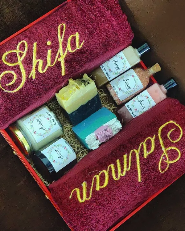This rich maroon and gold hamper is pure luxury. It includes bath towels personalized for 'Shifa' and 'Salman', along with a curated selection of body wash, shea butter, coffee scrub, bath salt, and handmade soaps. It’s a wedding gift that truly pampers.