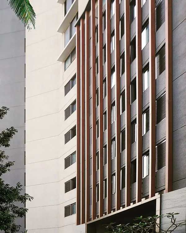 For The Bandra Project, we designed a simple yet practical façade using vertical wooden fins to conceal the parking floors, set against a stone-clad backdrop for a modern aesthetic.