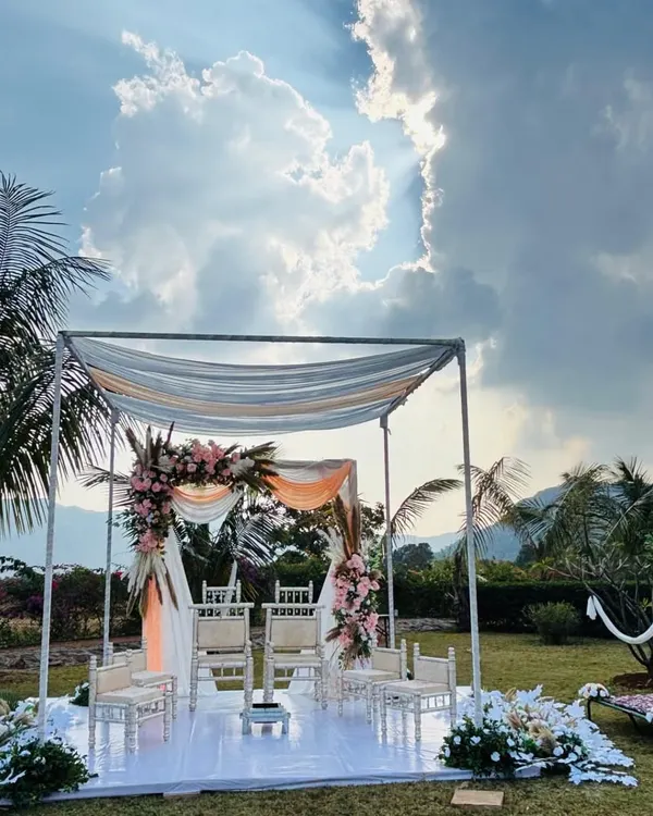A breathtaking view of the minimal mandap set against a dramatic sky in Lonavala. The simple structure with light draping allows the natural landscape to be a part of the decor.