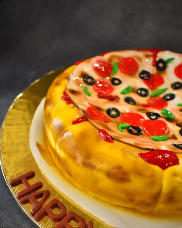 A close-up of the pizza illusion cake, showing the detail of the fondant "cheese," "pepperoni," and "olives." It's a Nutella chocolate chip cake designed to trick the eye and delight the taste buds.