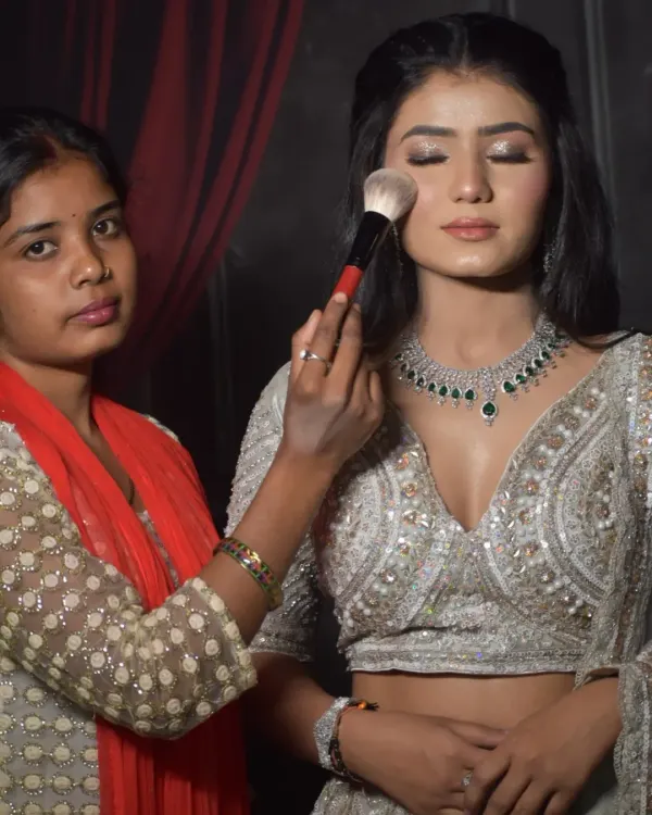 A student from my one-on-one course carefully applies finishing powder to a model's engagement look. This practical session focuses on creating a soft, glowing base that looks perfect in photos.