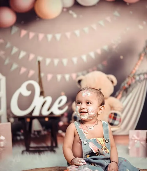A first birthday cake smash is a memory you will treasure forever. This little one is having the time of his life, covered in cake and happiness in a setup filled with balloons and teddy bears.