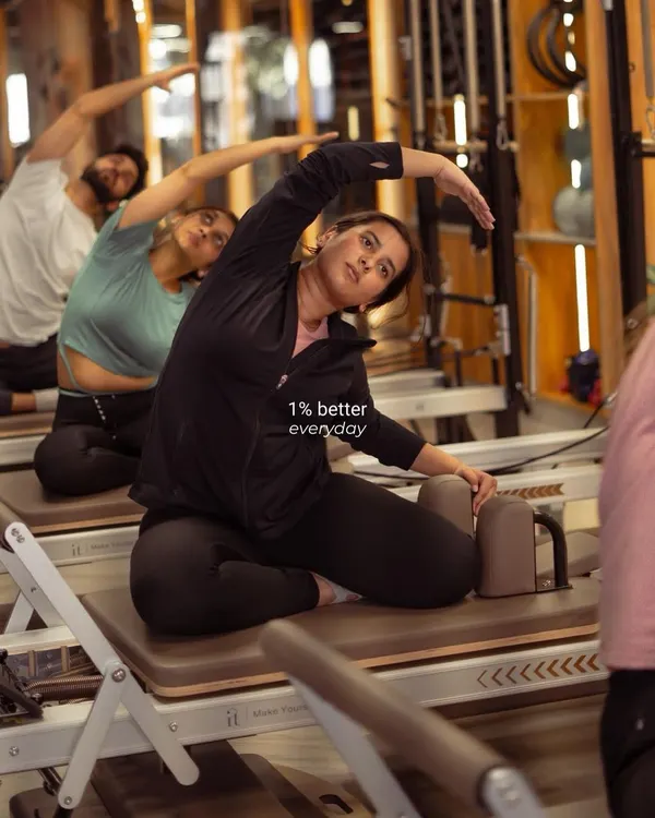 Progress isn't about giant leaps; it's about getting just 1% better every day. Here, a client focuses on a deep side stretch on the reformer, improving flexibility and control.