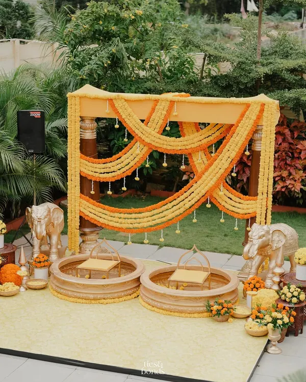 A traditional Haldi setup with a vibrant marigold backdrop. We used classic elements like urlis, brass bells, and elephant statues to create an auspicious and joyful setting for Ketaki and Rakesh's Haldi ceremony.