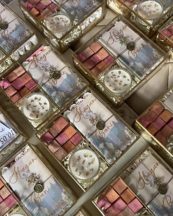 A stunning array of my glass box wedding invitation hampers. Each one is personalized with the couple's names and wedding date, containing gourmet sweets and a custom invitation card.