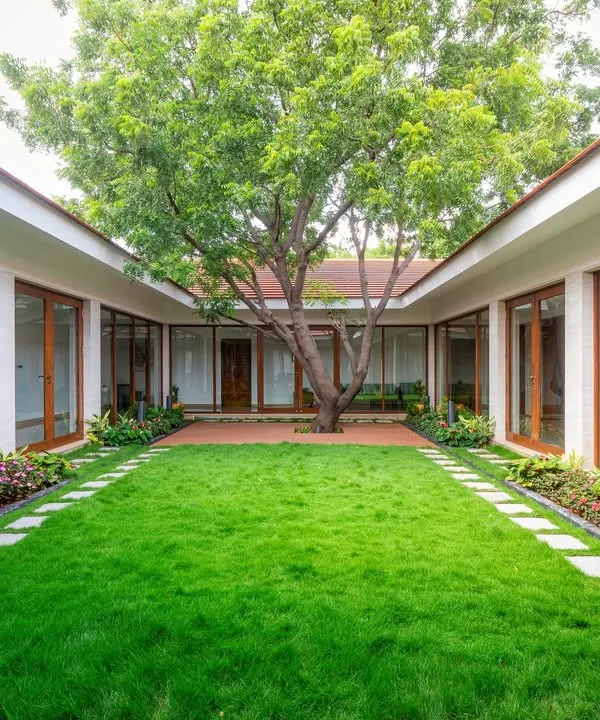 We design homes around light, air, and nature. This central courtyard, a modern interpretation of the traditional `mutram`, forms the green heart of this farmhouse, connecting all living spaces and creating a tranquil, private oasis for the family.