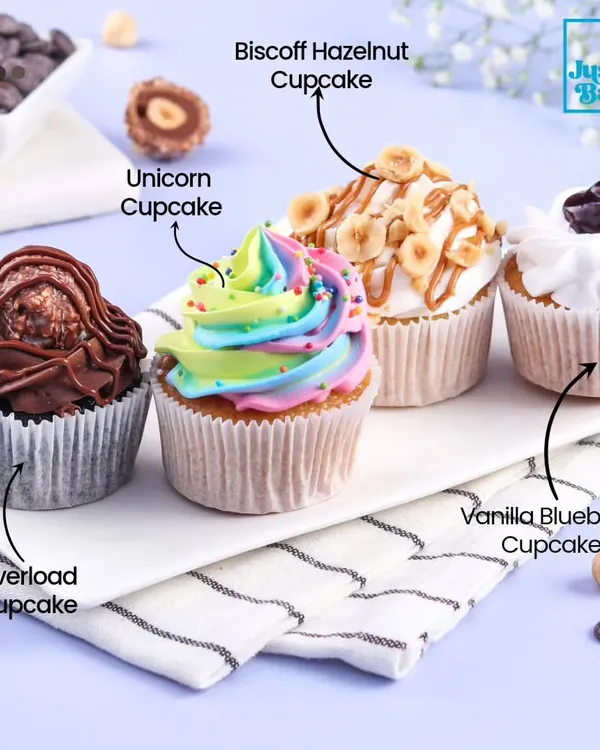 A lineup of some of our most popular cupcake flavors. This image showcases the variety we offer, including the decadent Overload, colorful Unicorn, nutty Biscoff Hazelnut, and fruity Vanilla Blueberry.