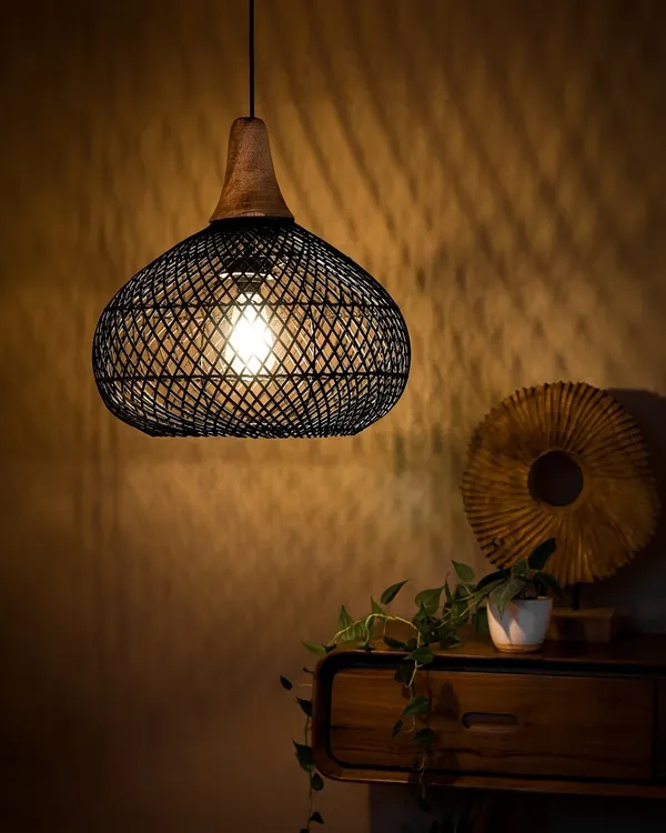 This black-dyed bamboo pendant, shown here in a cozy corner, demonstrates how a modern design can still create a warm, inviting atmosphere. The wooden top adds a touch of natural contrast, while the open weave casts beautiful, intricate shadows on the wall.