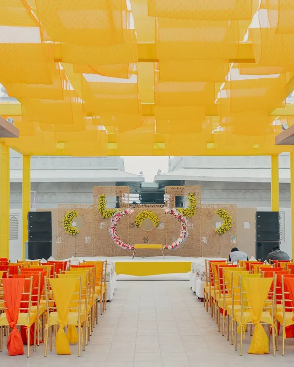 A vibrant Haldi ceremony setup at the Fairmont Jaipur. The space is filled with sunshine yellow, from the overhead fabric canopy to the chair ties, creating a cheerful and festive atmosphere for this joyous occasion.