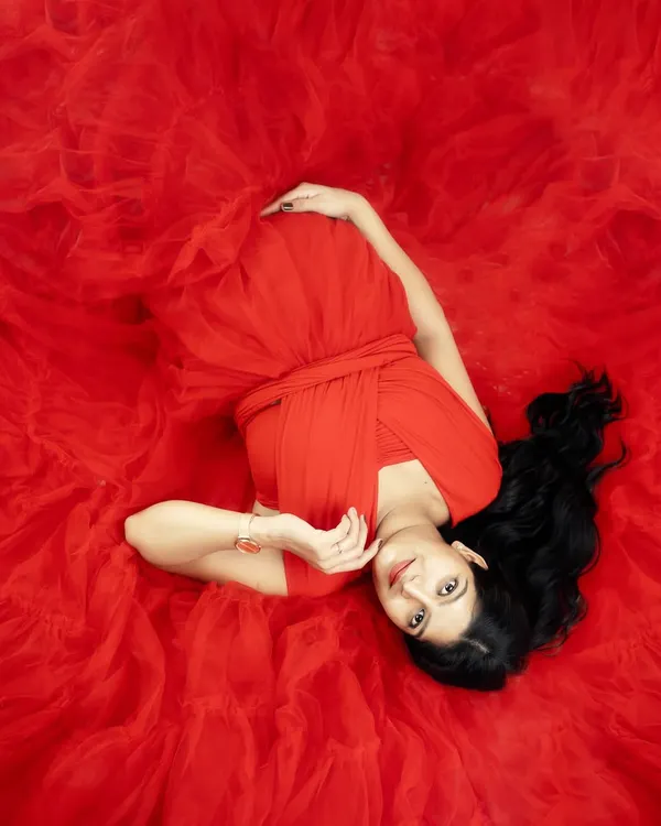 A portrait of motherhood, painted in vibrant red. This artistic top-down shot captures the beauty and drama of pregnancy, enveloping you in a sea of soft tulle.