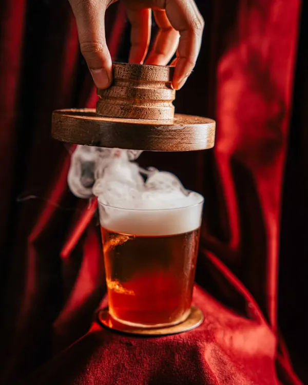 Creating atmosphere for a smoked cocktail at Amelia. We used dramatic lighting against a rich, red velvet background to highlight the billow of smoke, turning a simple drink into a theatrical experience and an unforgettable visual.
