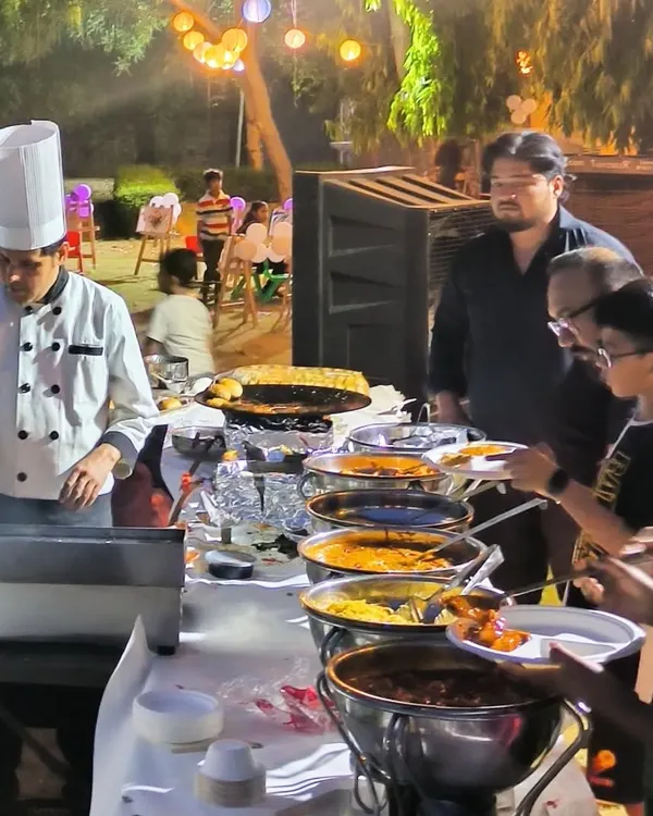 A guest favorite: our live cooking station. Here, a chef prepares a custom dish for a guest at an outdoor evening party, offering a personalized and engaging food experience.