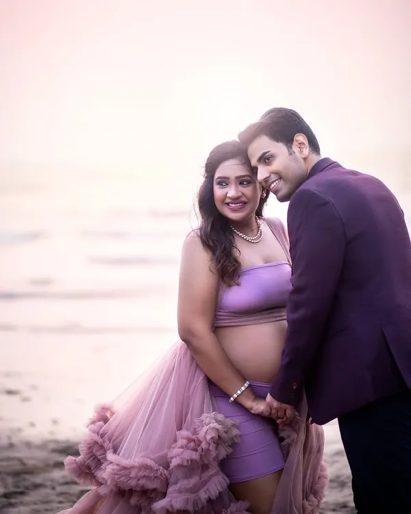 A tender moment on the beach as the sun sets. The soft, blush-toned light creates a romantic and dreamy atmosphere.