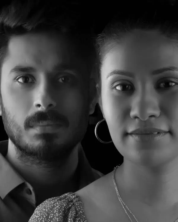 A powerful and direct black and white couple portrait. The dramatic lighting and serious expressions create a moody, high-fashion feel, perfect for couples wanting a creative pre-wedding shoot.