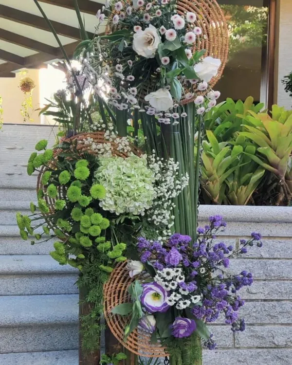 A modern, sculptural floral installation. This piece uses a vertical structure to showcase a variety of flowers and textures, from soft hydrangeas to bold green chrysanthemums, creating a living work of art.