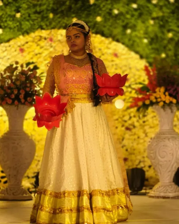 A dancer in traditional attire holds lotus-shaped diyas, ready to perform a welcome dance. This classic performance adds a touch of grace and auspiciousness to any wedding event.